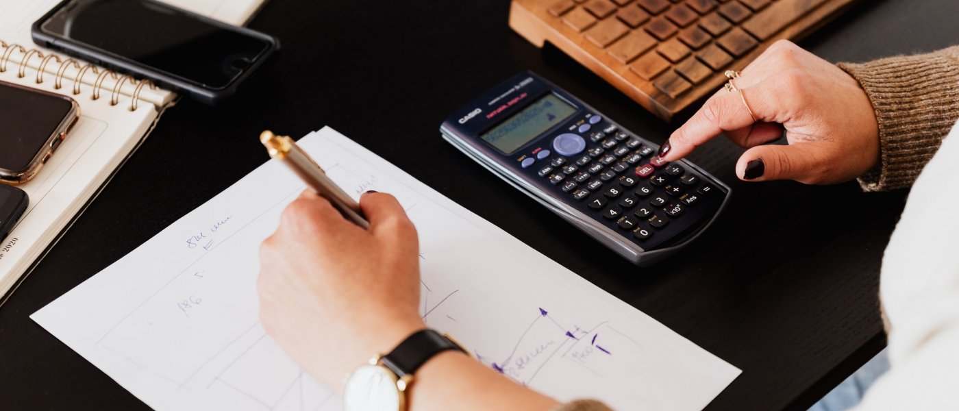 En person räknar på en miniräknare och skriver på ett papper
