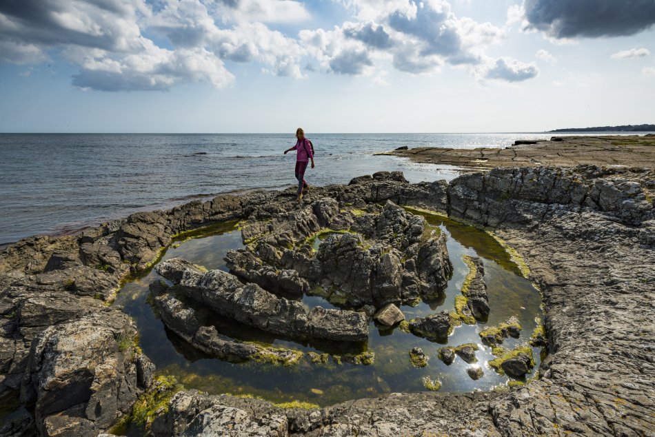 En person går på en stenformation vid havet